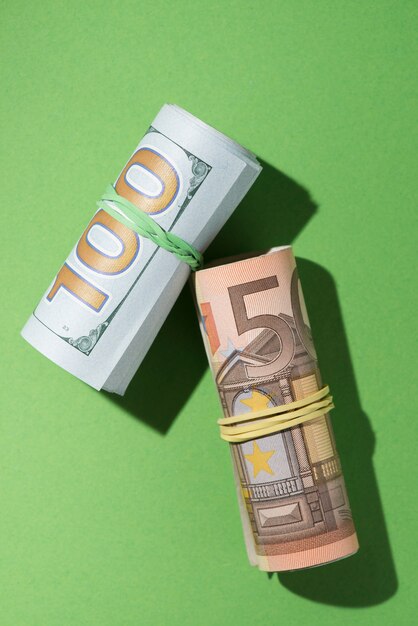 Overhead view of rolled up banknotes on green backdrop