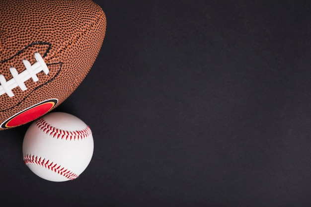 An overhead view of rugby ball and baseball on black background