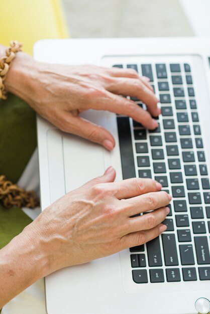 An overhead view of senior woman's hand typing on laptop keypad