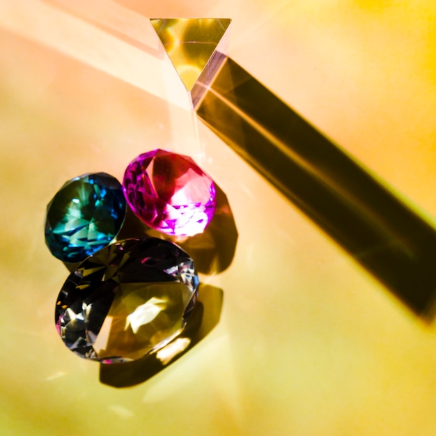 An overhead view of shiny pink; green and yellow diamonds on colored backdrop