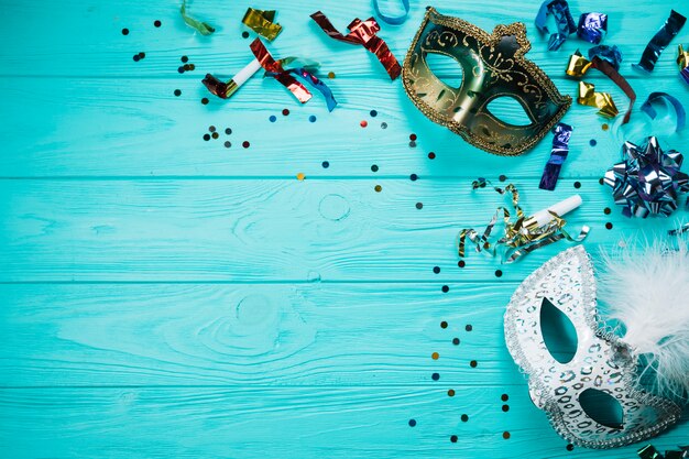 Overhead view of silver and golden masquerade carnival mask with party decorations on wooden table