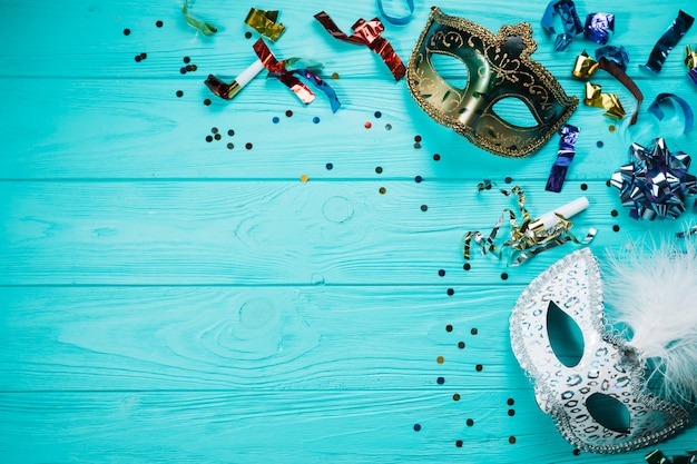 Overhead view of silver and golden masquerade carnival mask with party decorations on wooden table