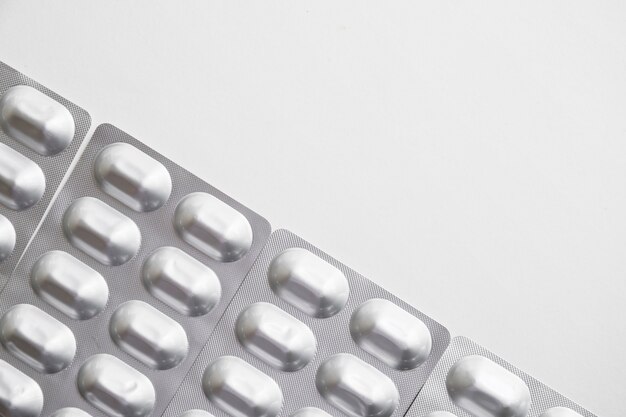 Верхний вид на блистерную упаковку из серебряных таблеток на белом фоне