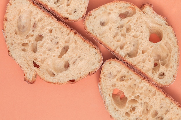 An overhead view slices of fresh bread on colored backdrop
