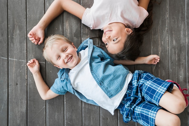 An overhead view of smiling boy and girl lying on hardwood floor