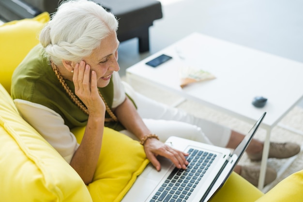 An overhead view of smiling senior woman using laptop