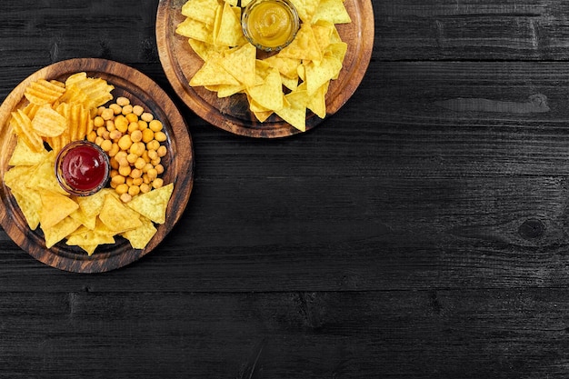 Overhead view of snacks with sauce on black wooden table.