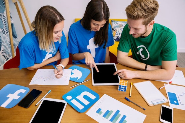 Overhead view of social media networking team looking at digital tablet