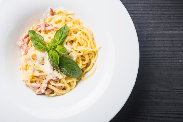 An overhead view of spaghetti with basil leaf and cheese toppings