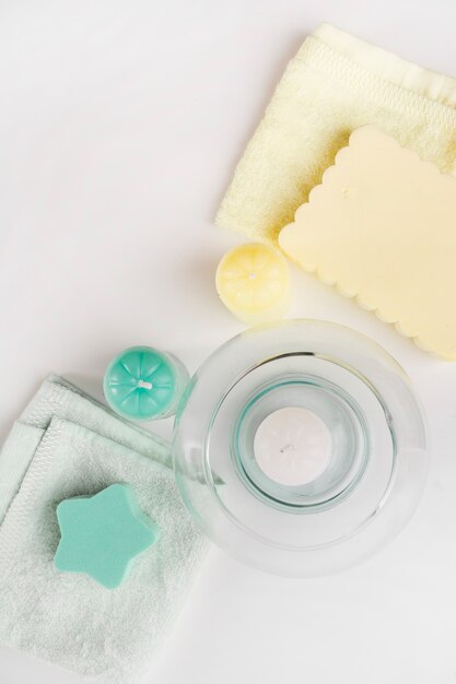 An overhead view of sponge over napkin decorated with different candles on white background