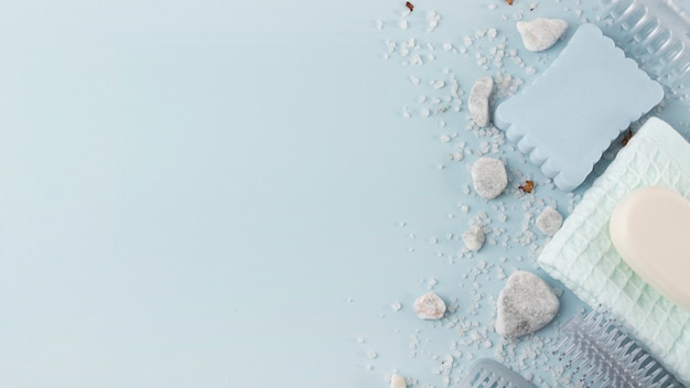 Free photo an overhead view of sponge; spa stone; napkin; salt and soap on blue background