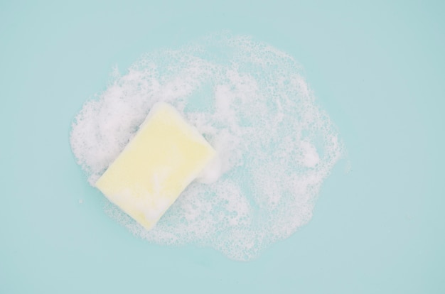 An overhead view of sponge with sud on blue background