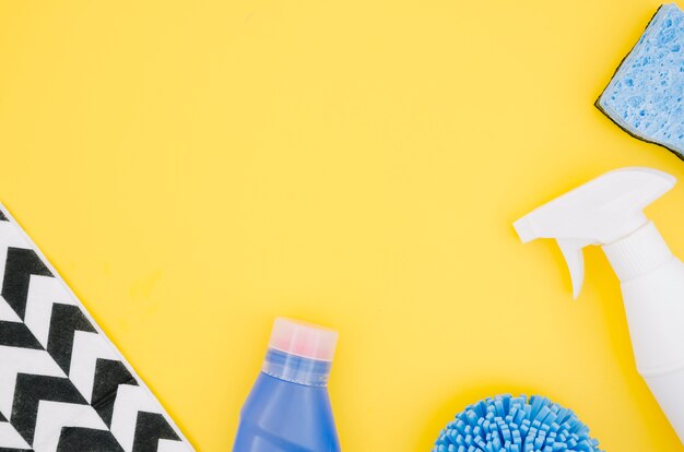 An overhead view of spray bottle and sponge on yellow backdrop