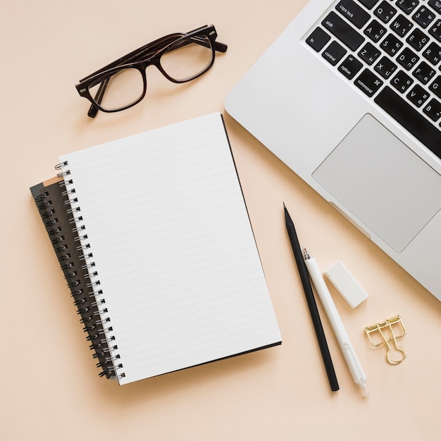 Overhead view of stationeries and laptop on beige background