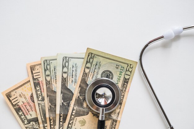 Overhead view of stethoscope on us currency note over white background