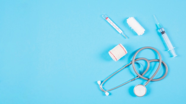 Overhead view of stethoscope with medical equipments on blue background