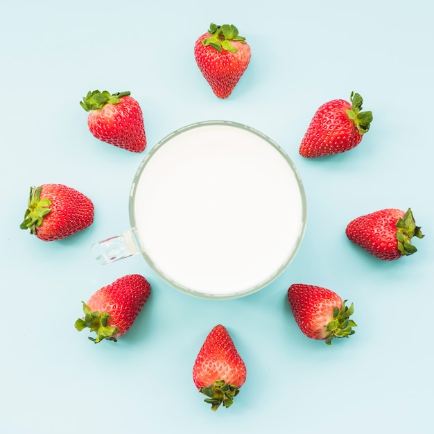 Overhead view of strawberries and milk on blue backdrop