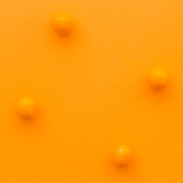 オレンジ色の背景に甘い円形キャンディーのオーバーヘッドビュー