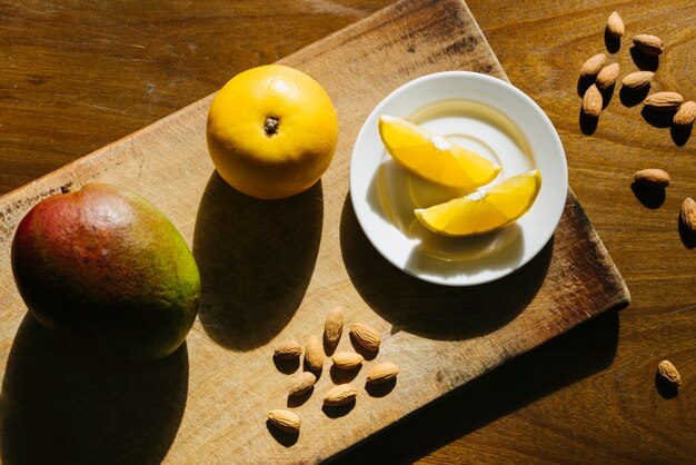 Overhead view of sweet lime and mango on wooden cutting board