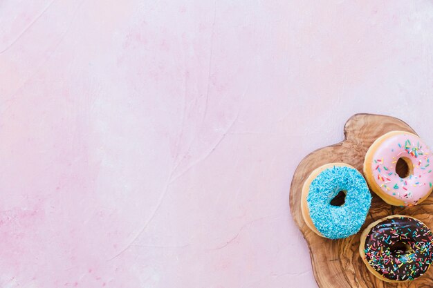 Overhead view of tasty donuts on wooden chopping board