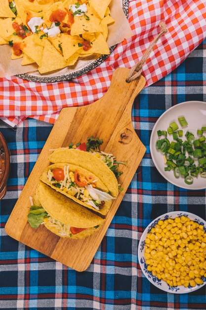 Overhead view of tasty mexican nachos and tacos on table cloth