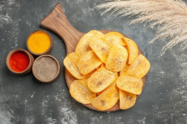 Overhead view of tasty potato chips spices with ketchup on gray table