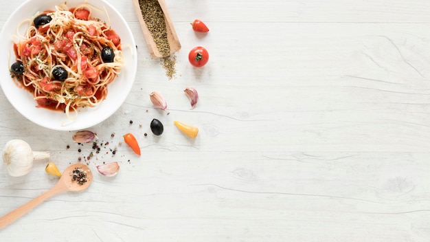 Overhead view of tasty spaghetti pasta and fresh aromatic ingredients on table