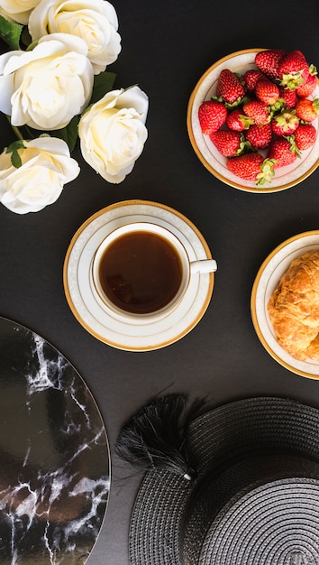 Overhead view of tea cup with strawberries and bread