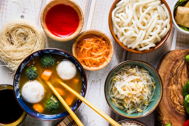 우동 국수와 태국 생선과 야채 그릇 수프의 오버 헤드보기; 화이트 책상에 소스와 콩나물