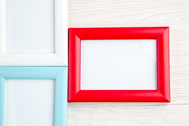 Overhead view of three empty picture frames in different colors on stripped
