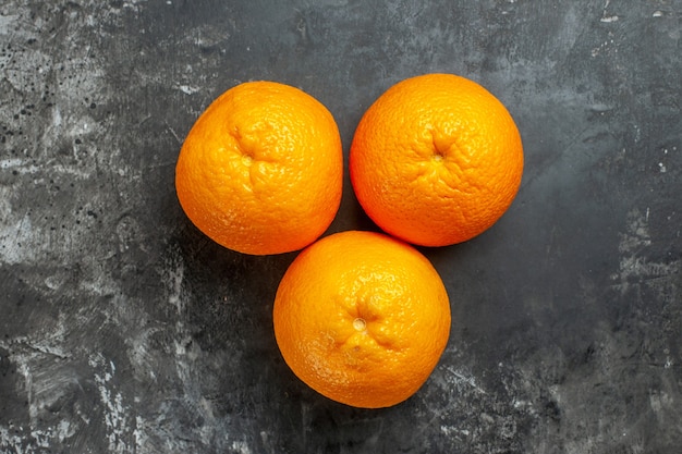 Вид сверху трех натуральных органических свежих апельсинов на темном фоне
