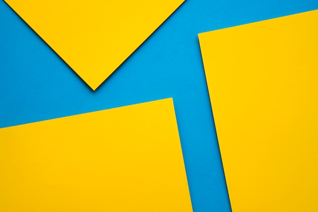 Overhead view of three yellow craftpapers on blue background