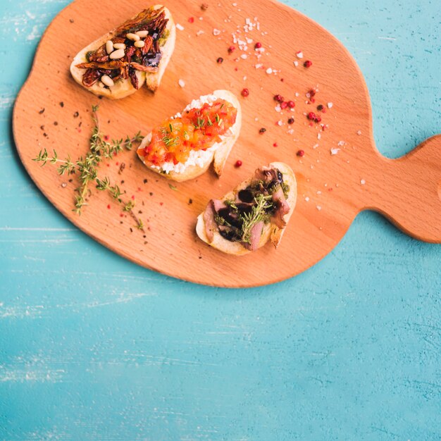 An overhead view of toasted sandwiches with thymes; peppercorn and salt on chopping board