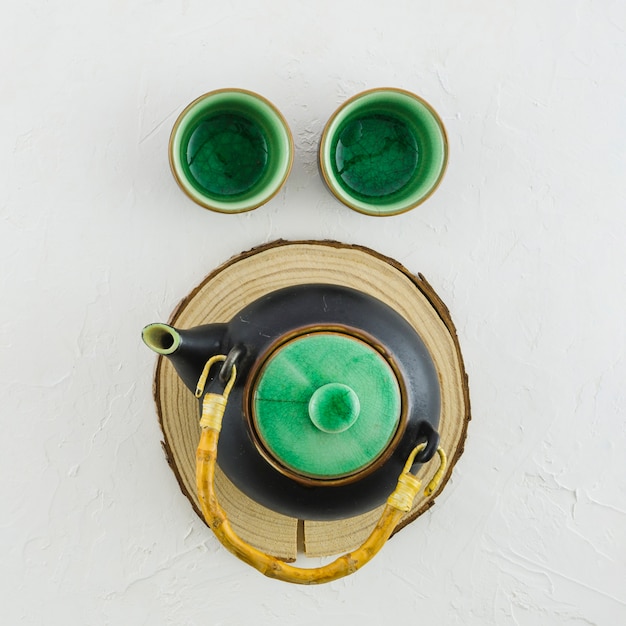 An overhead view of traditional teapot and two cups on white background