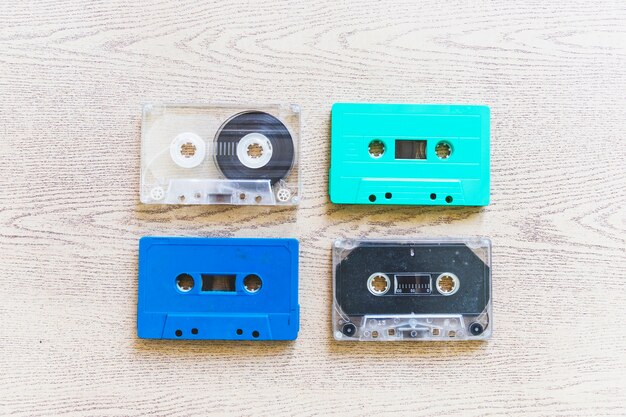 An overhead view of transparent; blue and turquoise colored cassettes on wooden background