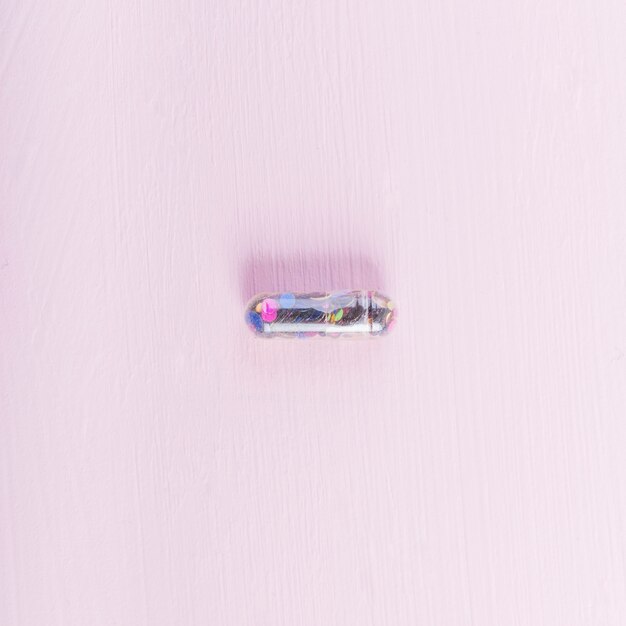 분홍색 배경에서 투명 장식 조각 캡슐의 오버 헤드보기