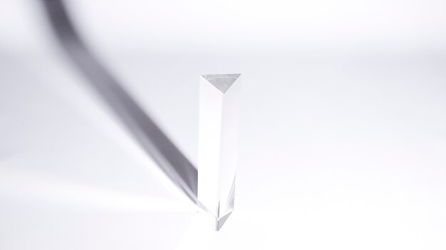 An overhead view of triangular prism with dark shadow on white background