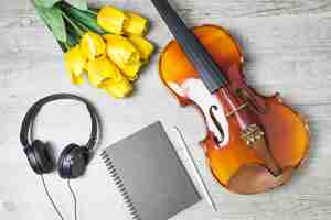 Free photo overhead view of tulips; diary; pencil and violin on wooden background