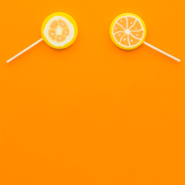 オレンジの背景に2つの柑橘類の棒付きキャンデーのオーバーヘッドビュー