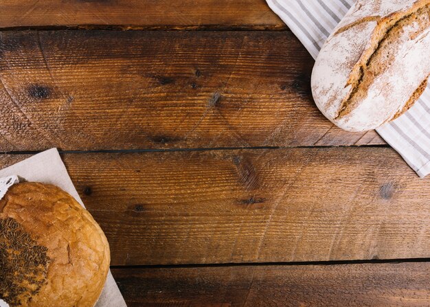 An overhead view of two different type of bread on wooden background