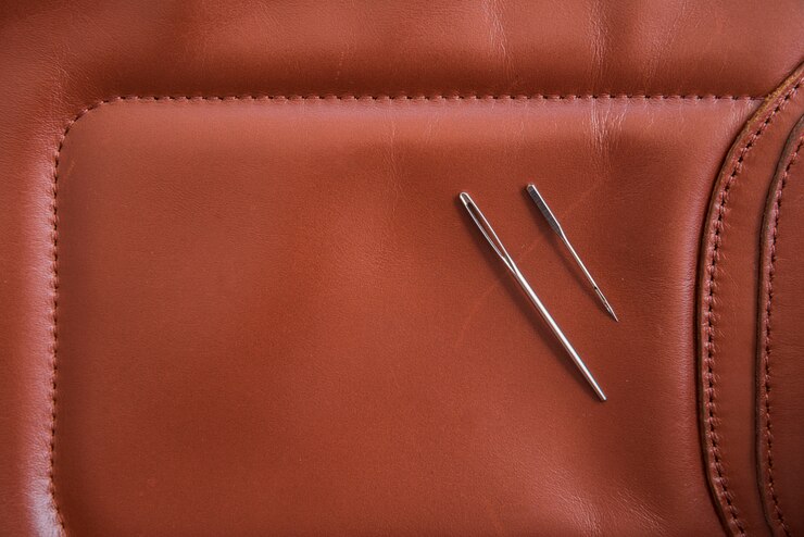 मुफ़्त फोटो an overhead view of two needles on brown leather