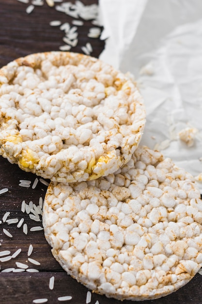 An overhead view of two puffed rice cake with grains on wooden desk