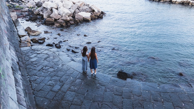 An overhead view of two young women standing near the coast