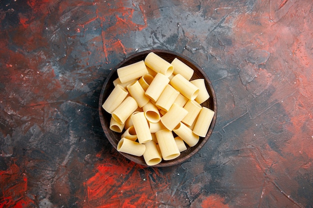 Overhead view of uncooked pastas inside the pot on black table