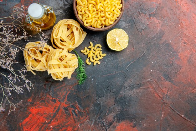 Free photo overhead view of uncooked three spaggeties and green oil bottle on mixed color table