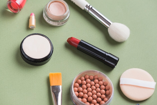 Overhead view of various cosmetic products on green background