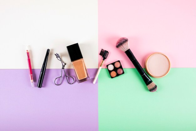 Верхний вид различных косметических продуктов на многоцветном фоне
