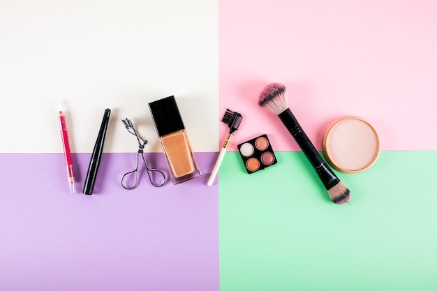 Overhead view of various cosmetic products on multi colored background