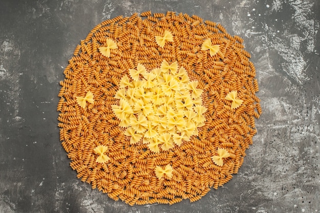 Overhead view of various kinds of raw Italian pastas arranged in a circle on gray background