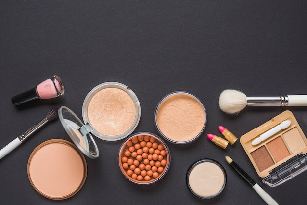 Overhead view of various makeup products on black surface